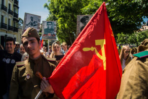 A uniformed man carrying a communist flag during the